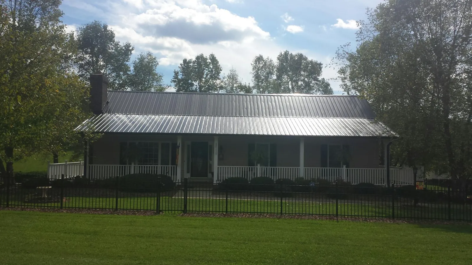 Gray metal roof on a brick ranch with a full width front porch — Gutter Guard Installation work by our crew in Enterprise